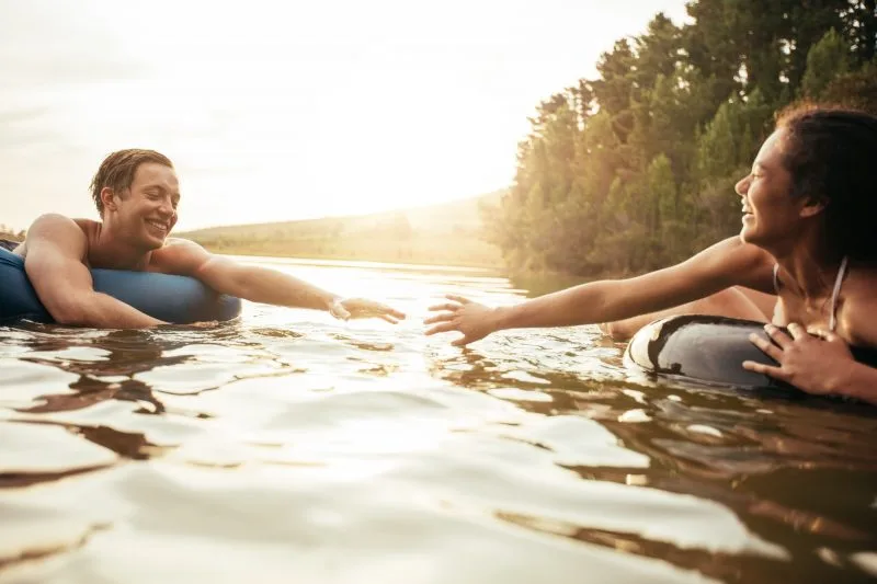 Young couple floating on inner tubes in lake