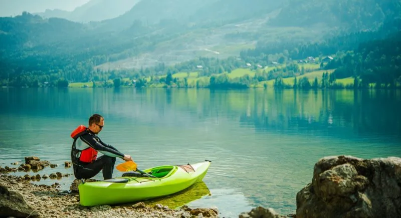 Man Relaxing By Lake After Long Day Of Canoeing.